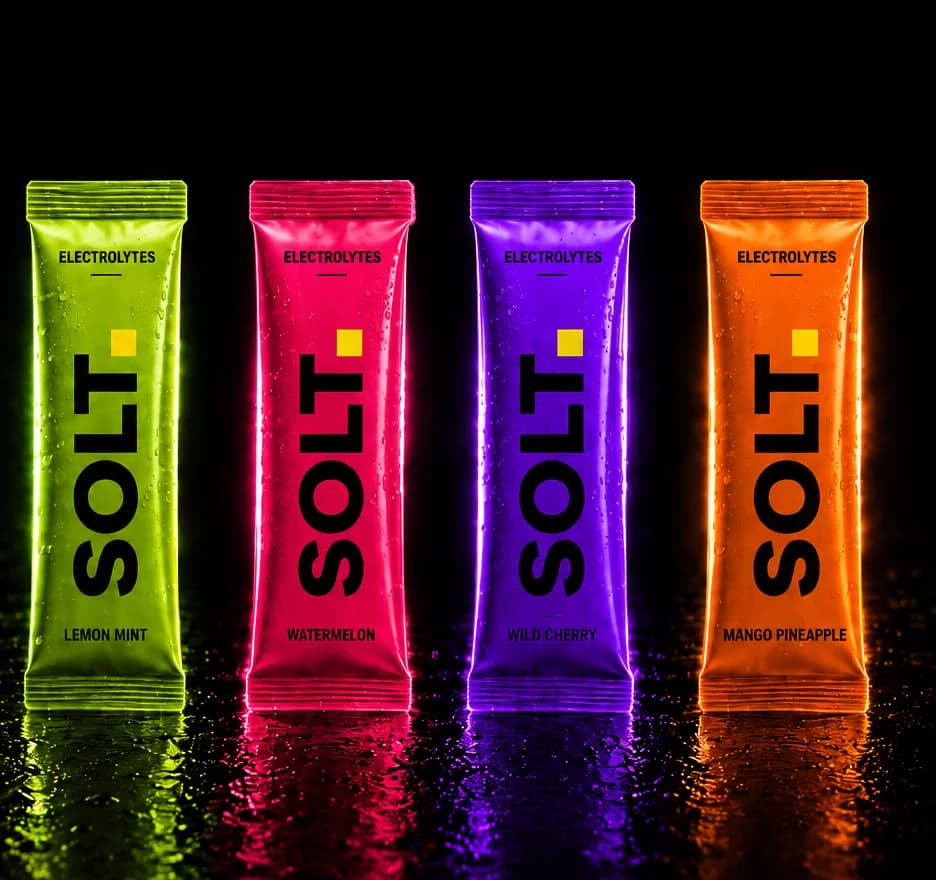 The SOLT electrolyte range, four single-serve sachets in green, pink, purple and orange on a dark surface.